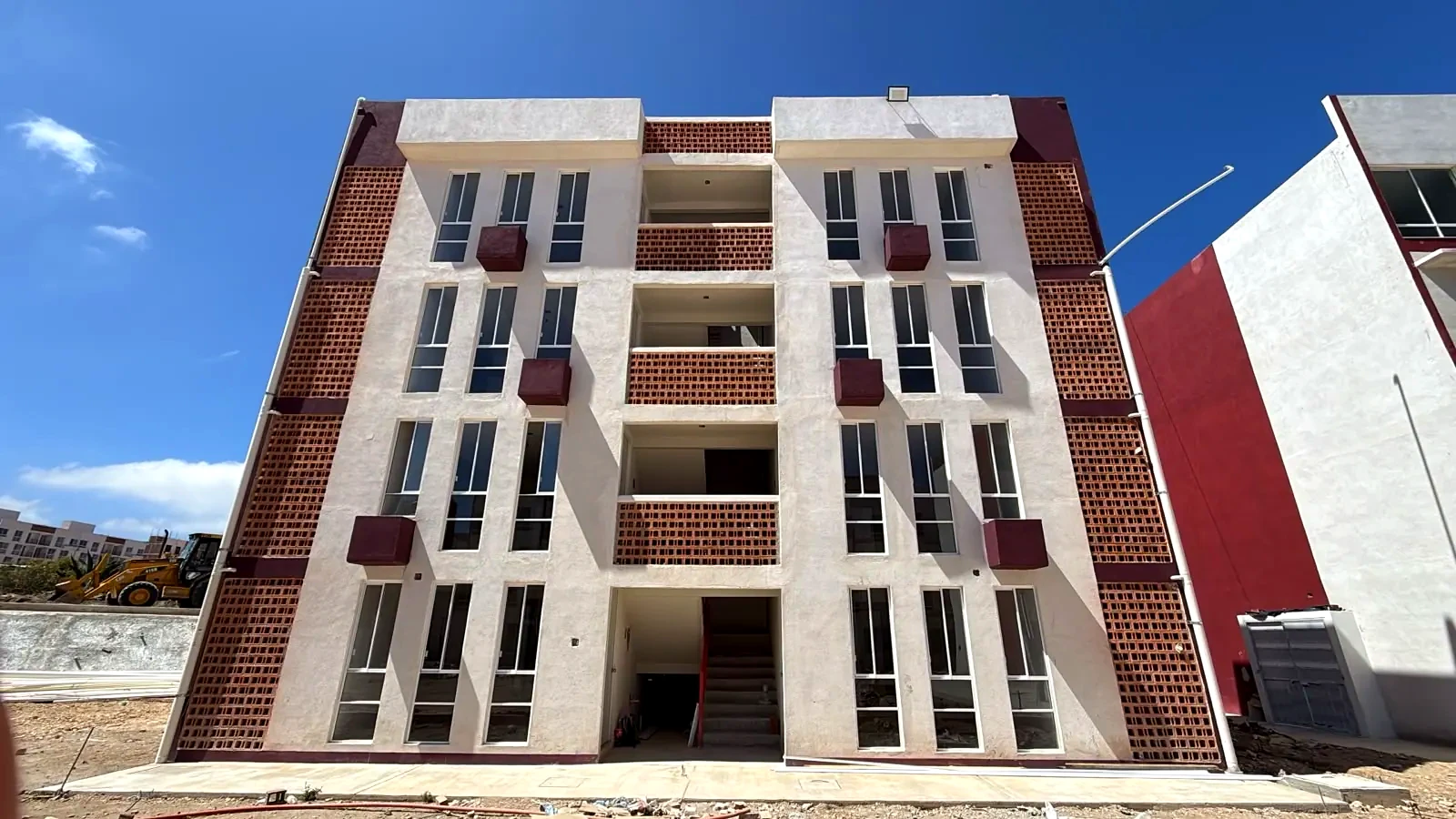 Edificio del desarrollo habitacional Ayotlán con fachada blanca y volúmenes en color vino