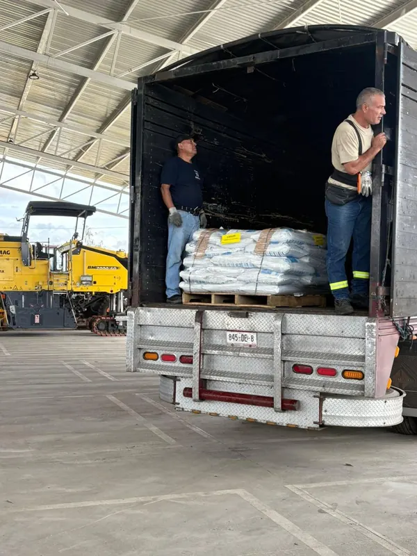 Dos trabajadores con una tarima de sacos de microesfera dentro de un camión