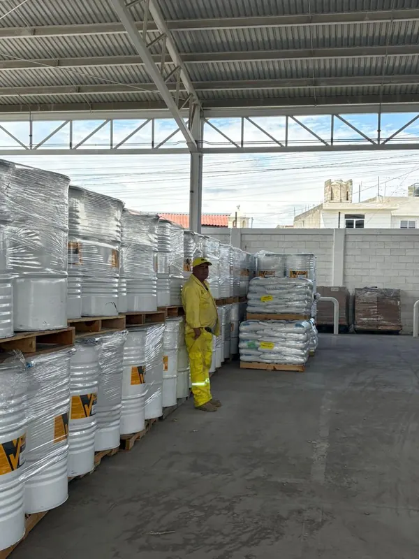 Trabajador junto a tambos de pintura de tráfico y tarimas de microesfera