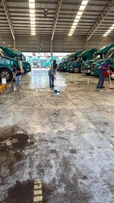 Piso de concreto con manchas en su estado inicial, con trabajadores lavando la superficie